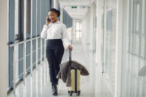 black woman with carry on suitcase on the phone