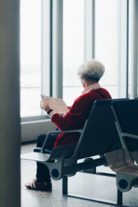 old lady reading paper in airport terminal